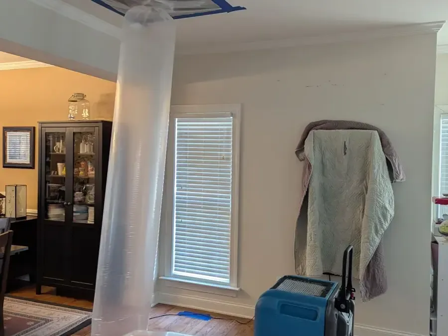 Clear containment tubing rises toward a ceiling beside blue drying equipment