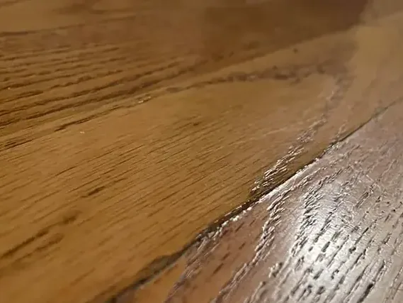 Wood floorboards show raised seams and uneven edges in a close view
