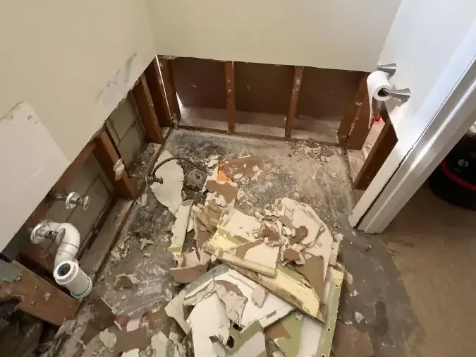Lower bathroom walls are opened with broken drywall scattered across the floor