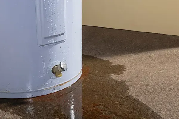 Water pooling at the base of a leaking tank water heater